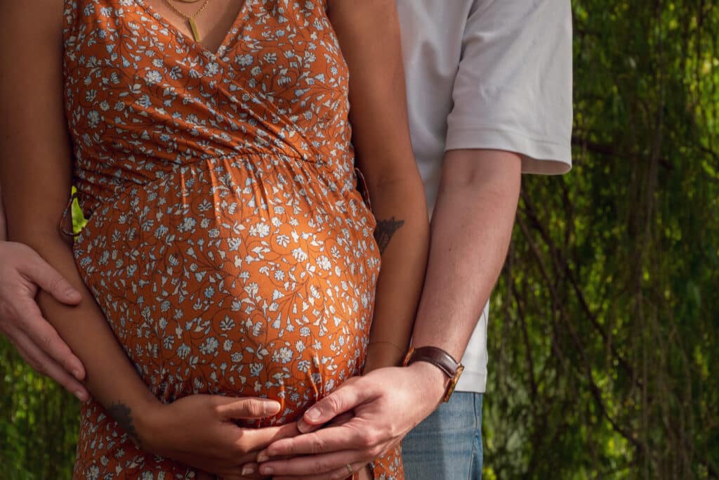Futurs parents, mains posées sur le ventre rond, séance photo grossesse dans le Morbihan